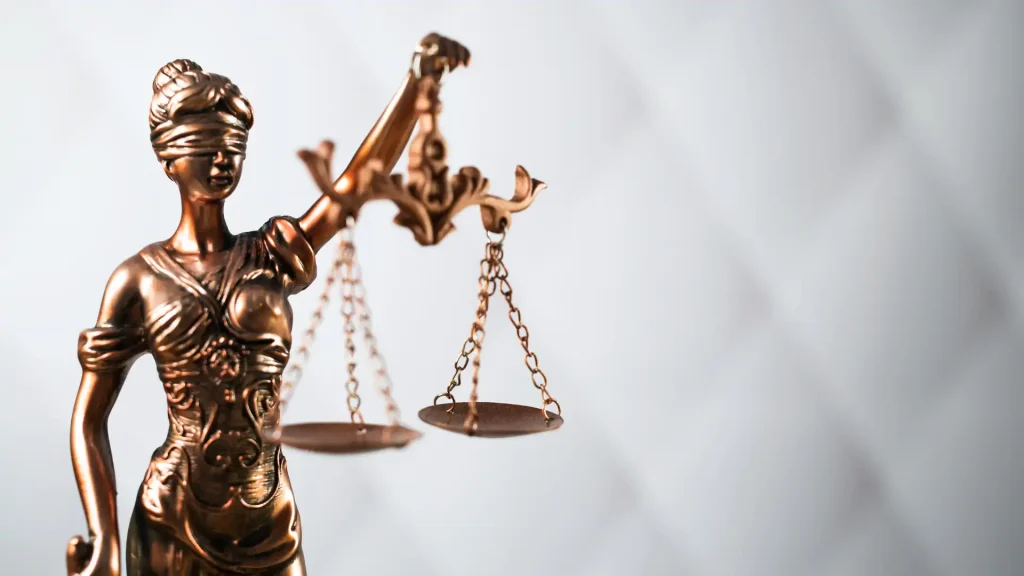 Bronze statue of Lady Justice holding scales of justice on white background