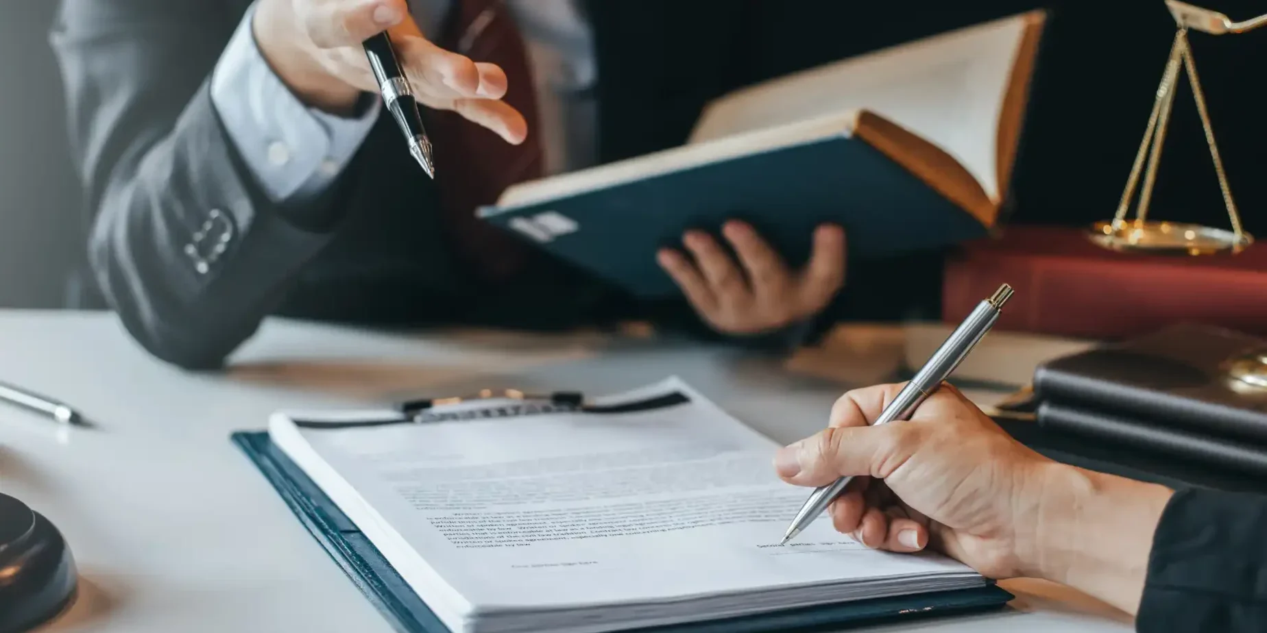 A person signing an agreement in front of a lawyer