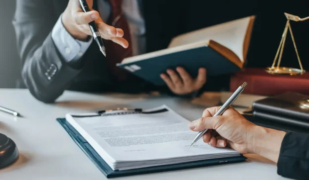 A person signing an agreement in front of a lawyer