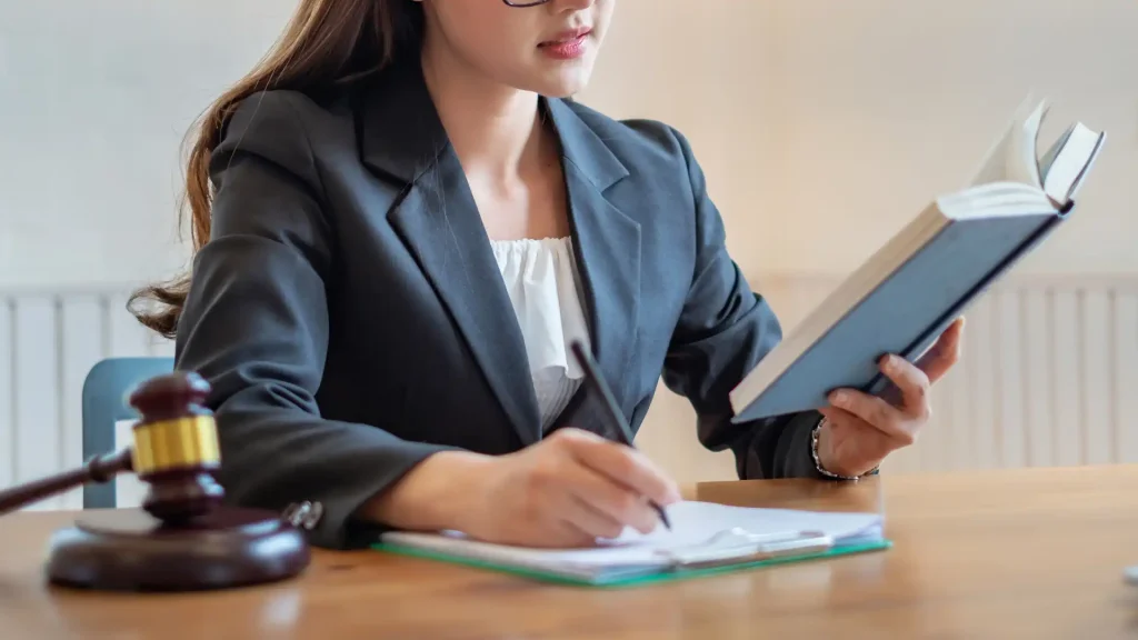 a lawyer writing on a paper while reading from a book