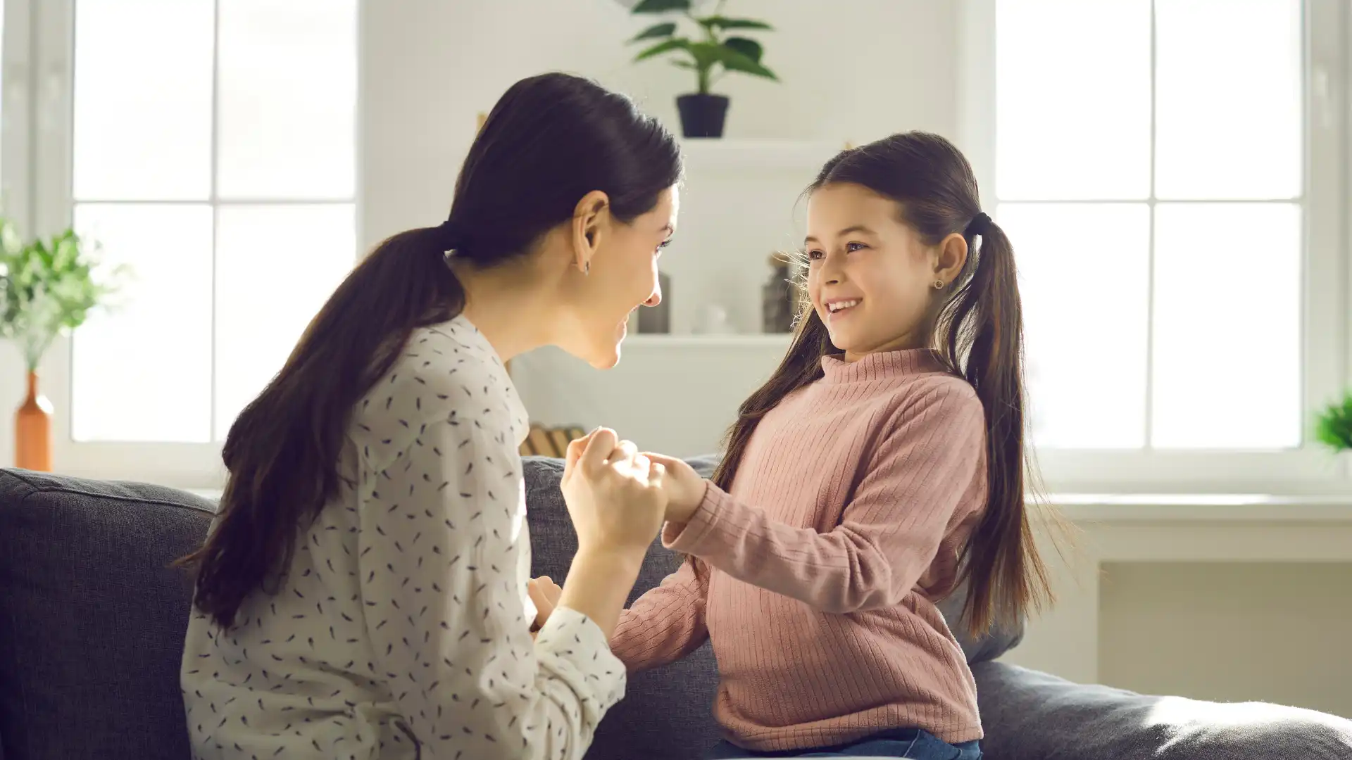 Mother holding daughter's hand while smiling and talk about adoption