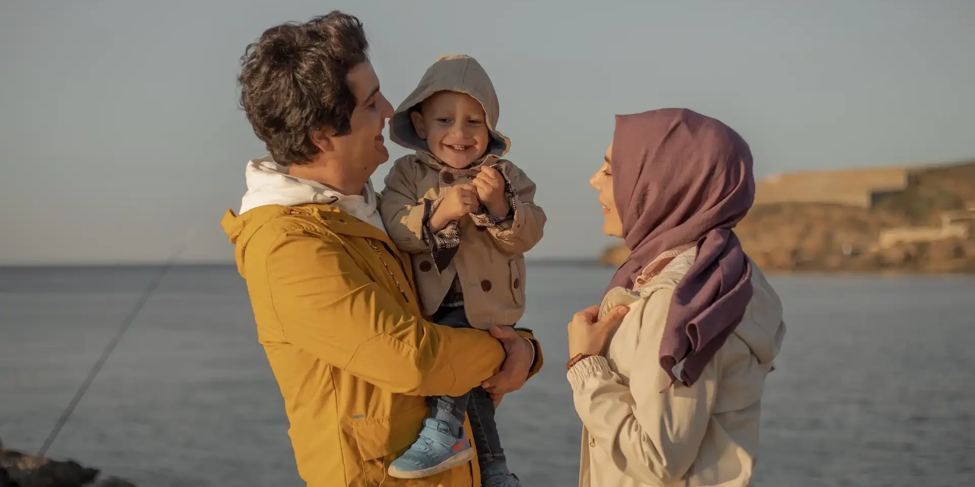 A couple smiling with their child near the lake