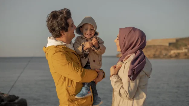 A couple smiling with their child near the lake
