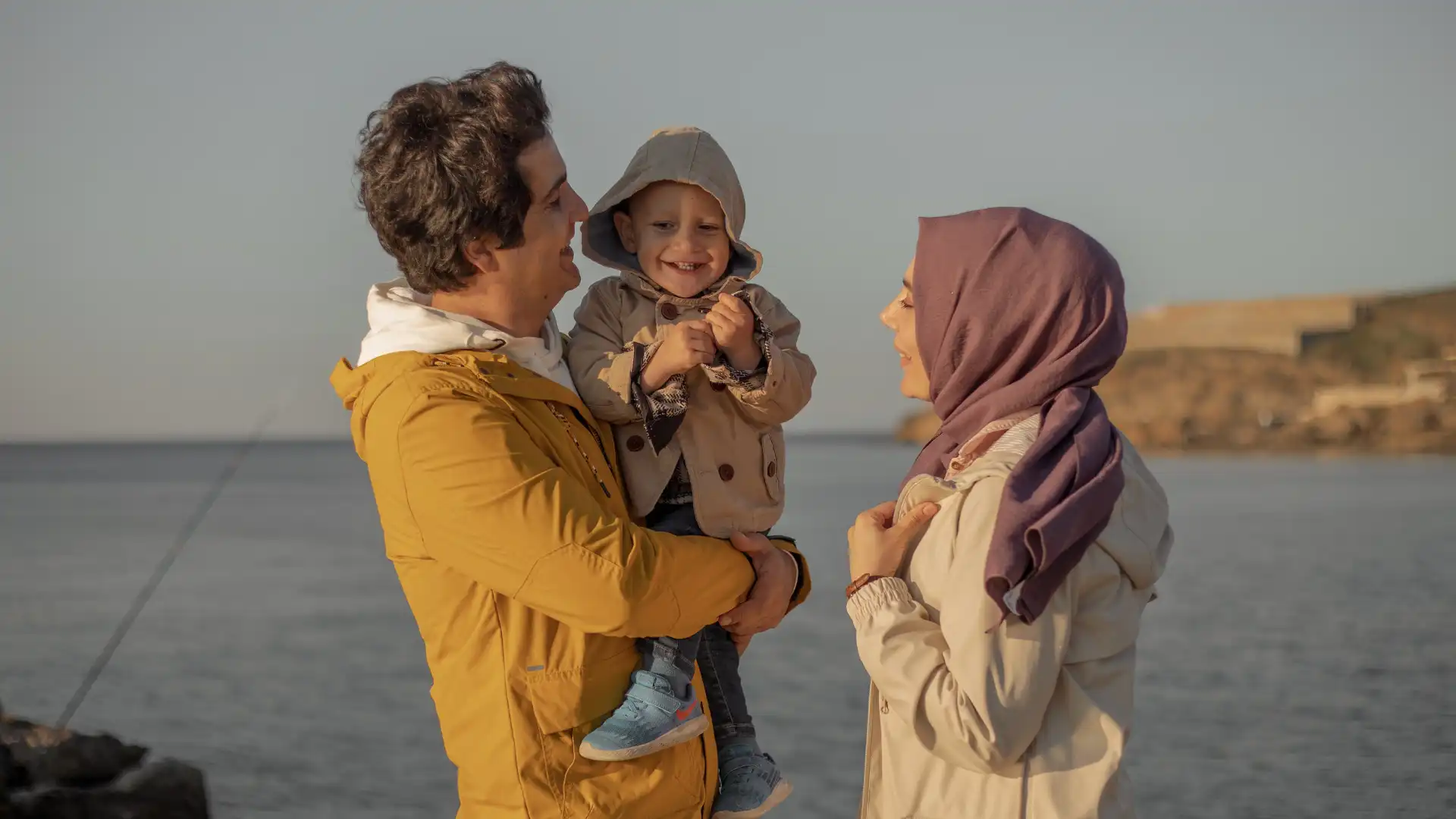 A couple smiling with their child near the lake