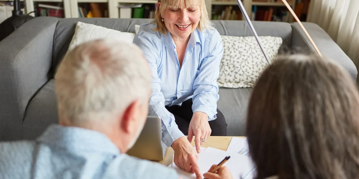 An attorney pointing husband and wife where to sign on a document