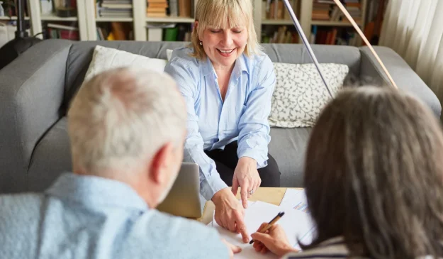 An attorney pointing husband and wife where to sign on a document
