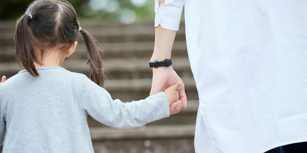 Parent holding their child's hand while walking.