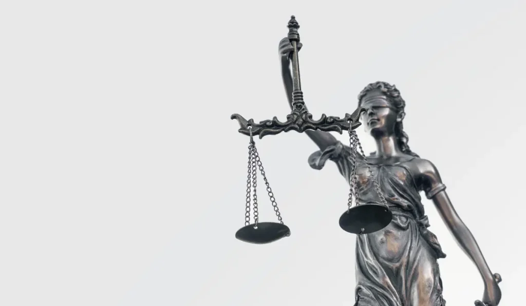 Silver statue of Lady Justice holding scales of justice on white background