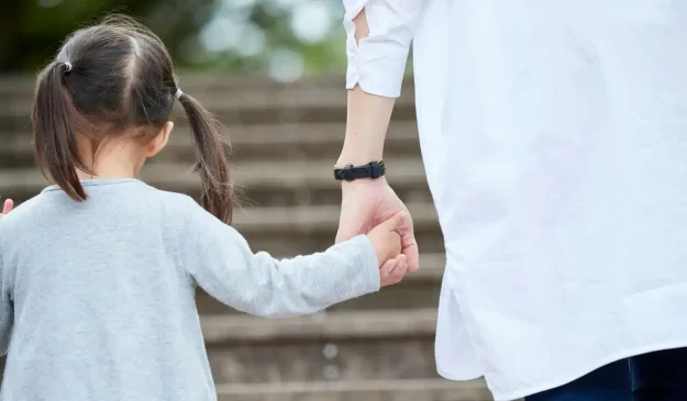 a child holding their parent's hand while walking up the stairs.