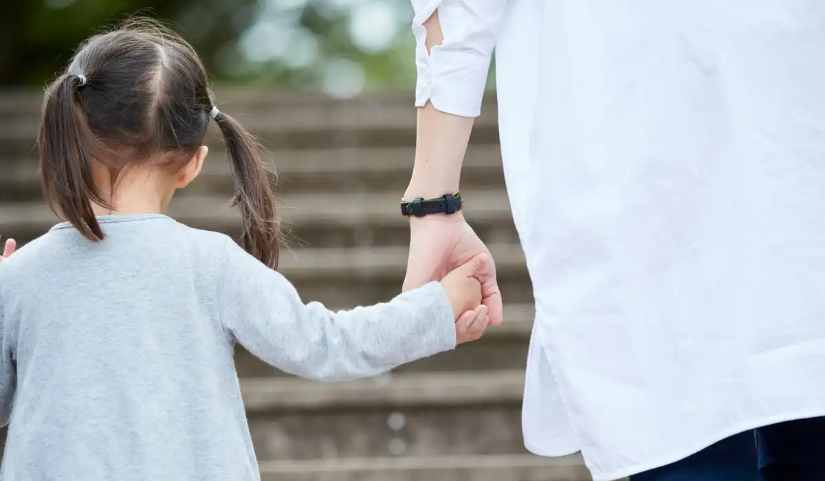 a child holding their parent's hand while walking up the stairs.