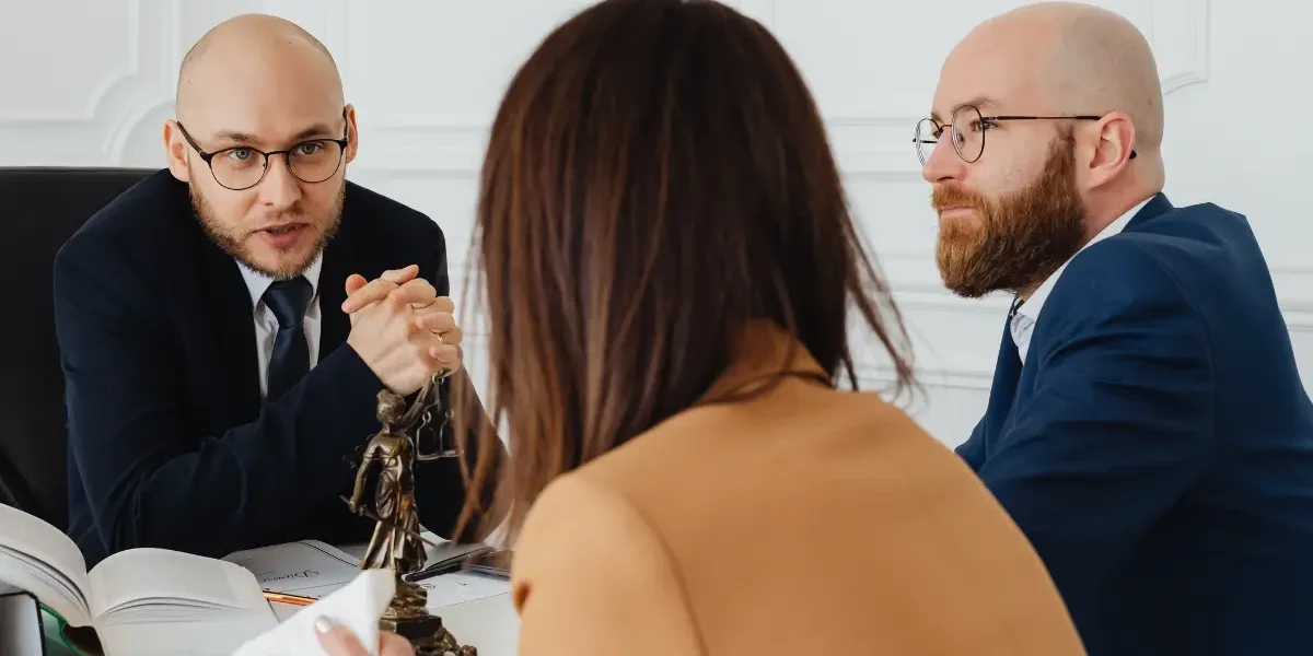 Two people speaking to a family lawyer in an office.