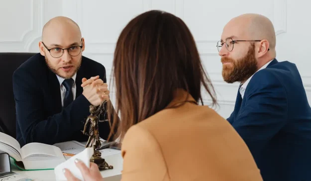 Two people speaking to a family lawyer in an office.