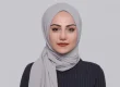Woman wearing a grey hijab against a plain background
