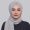Woman wearing a grey hijab against a plain background