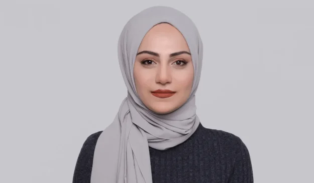 Woman wearing a grey hijab against a plain background