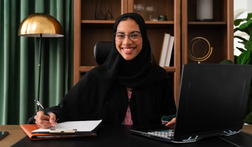 A lawyer in a black hijab working at a desk with a laptop