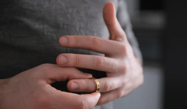 Person removing a wedding ring from their finger
