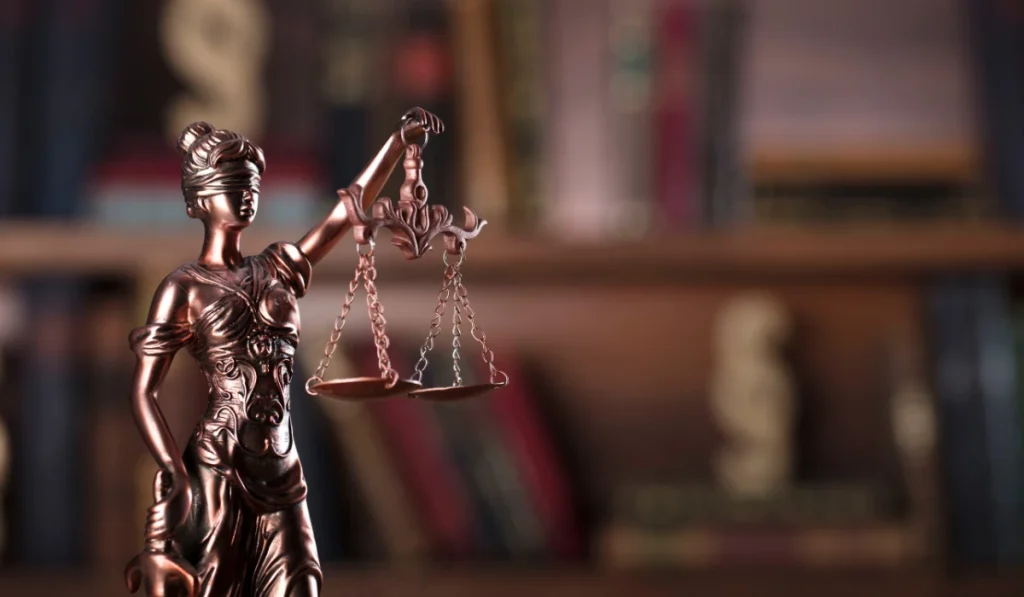 Lady Justice statue holding scales in front of law books